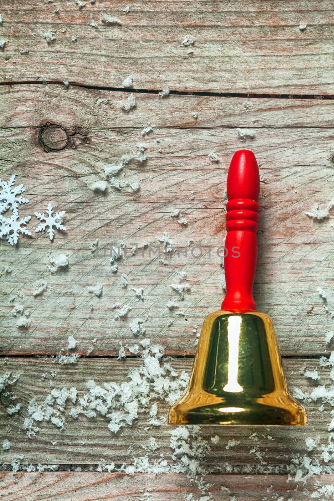 Colorful red hand bell with snowflakes on old wooden boards for a rustic country style Christmas background with copyspace