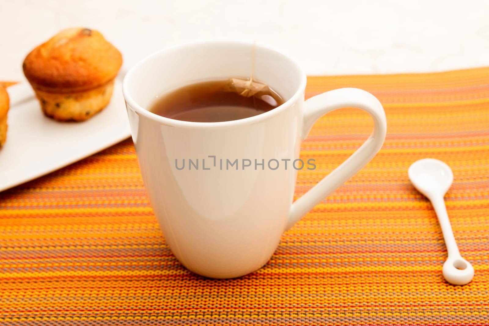 Vanilla with chocolate chips Muffins on a white plate with  a cup of tea.
