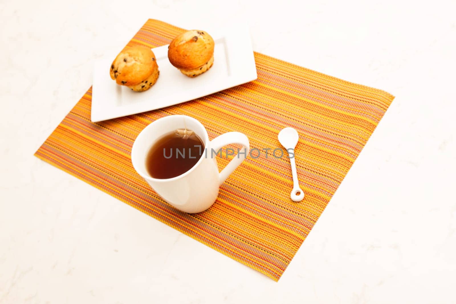 Vanilla with chocolate chips Muffins on a white plate with  a cup of tea.
