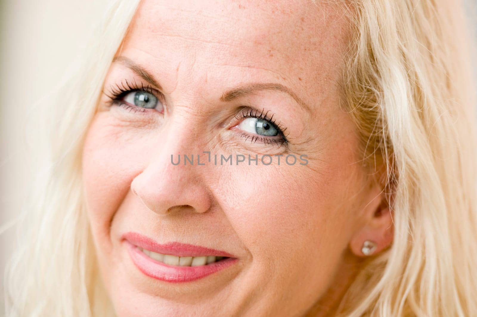 Close-up of a blonde woman middle-aged frontally smiling into the camera