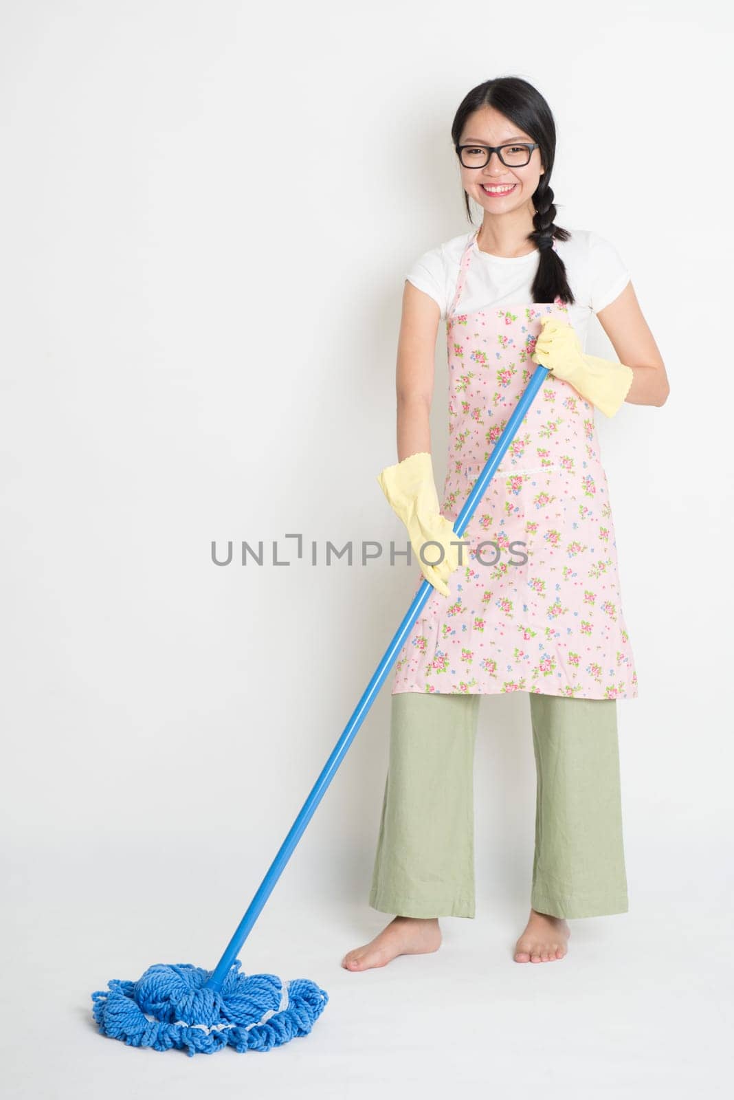 Full length Asian Chinese girl housekeeping, mopping floor on plain background.