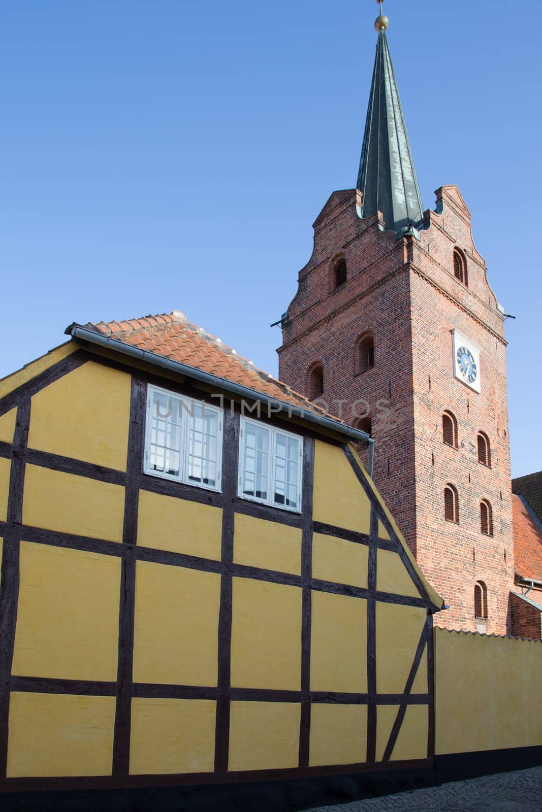 Church of Rudkabing behind a yellow half-timbered house