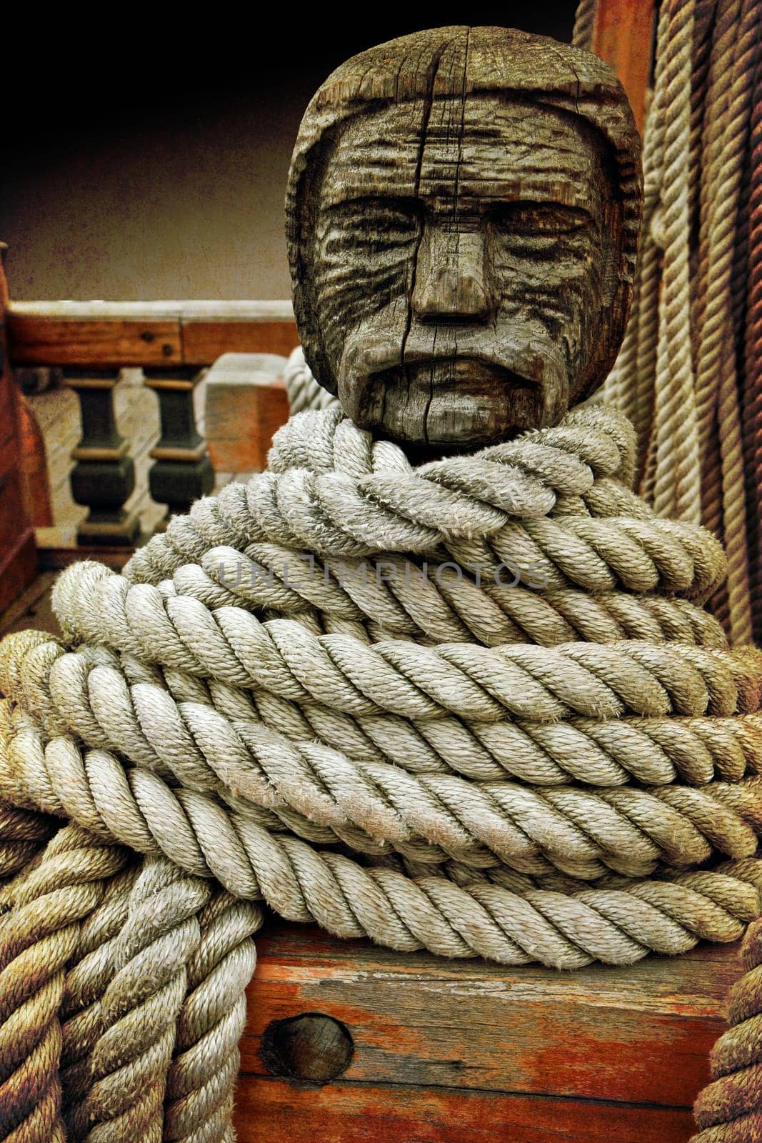 Head shaped wooden cleat on an old sailboat with ropes loop around it