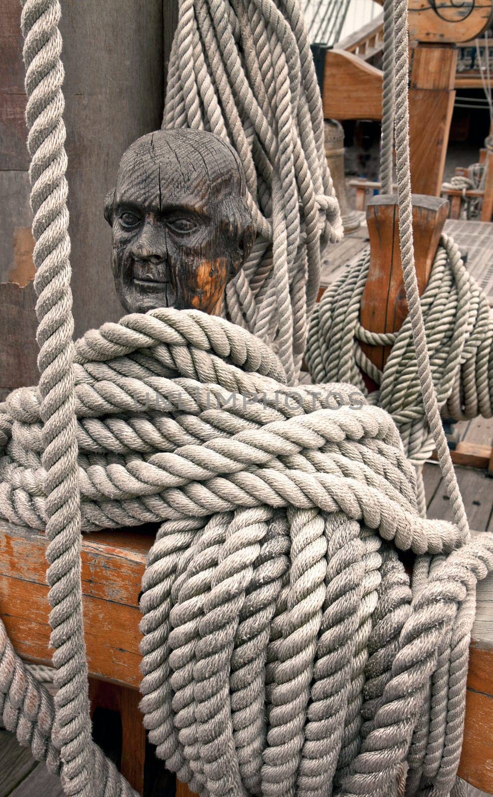 Ropes around a head shaped wooden cleat on an old vessel