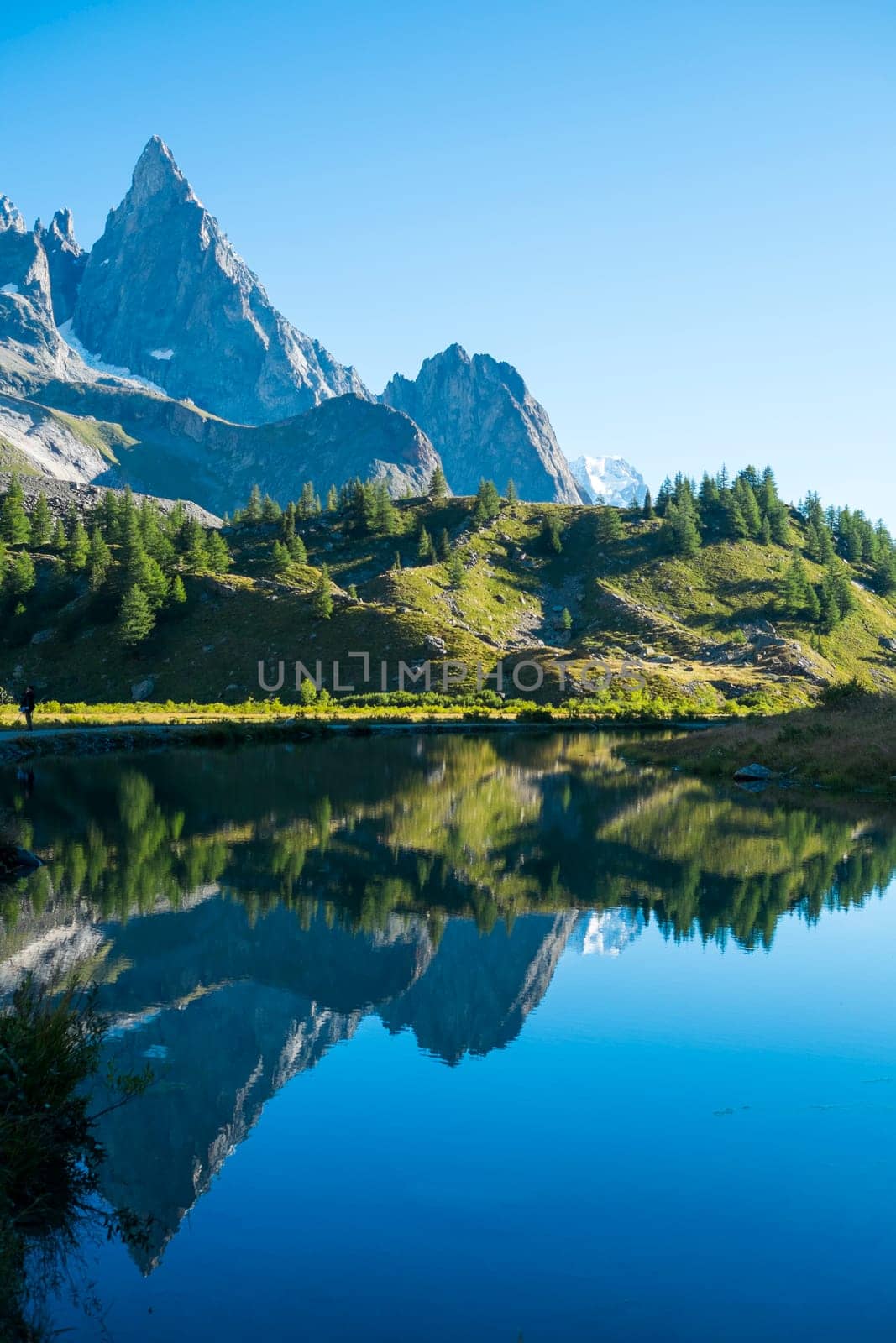 Combal Needles reflected on Combal Lake water on a sunny day in Val Veny, in Italy.