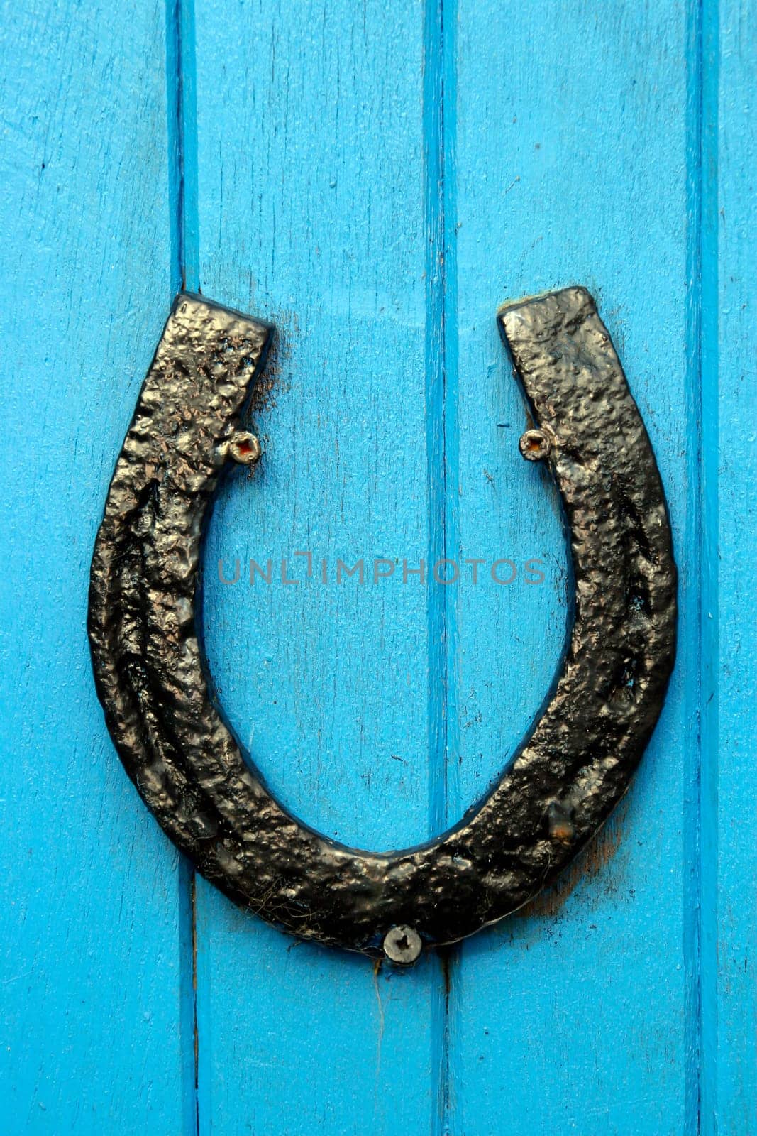 black horseshoe nailed to blue painted wooden boards on a door or wall
