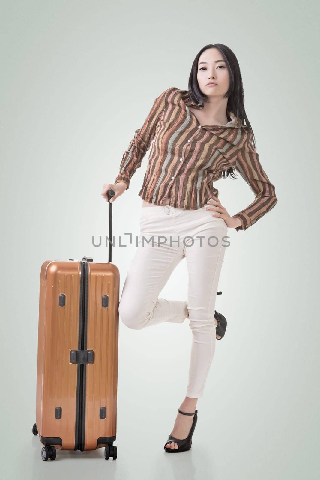 Modern Asian woman stand with a luggage, full length portrait on white background.