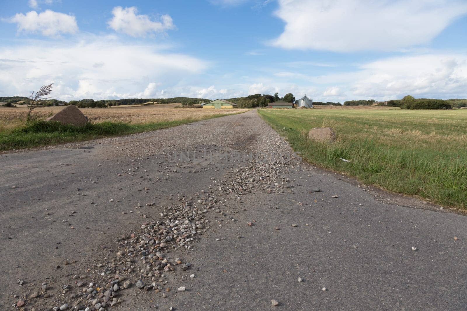 Long rocky dirt road leading to a farm in the field