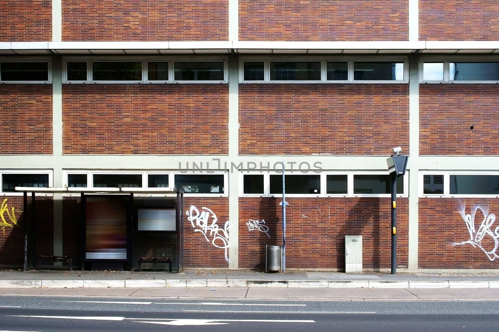 The photograph of a bus stop on a strikingly brick house wall.