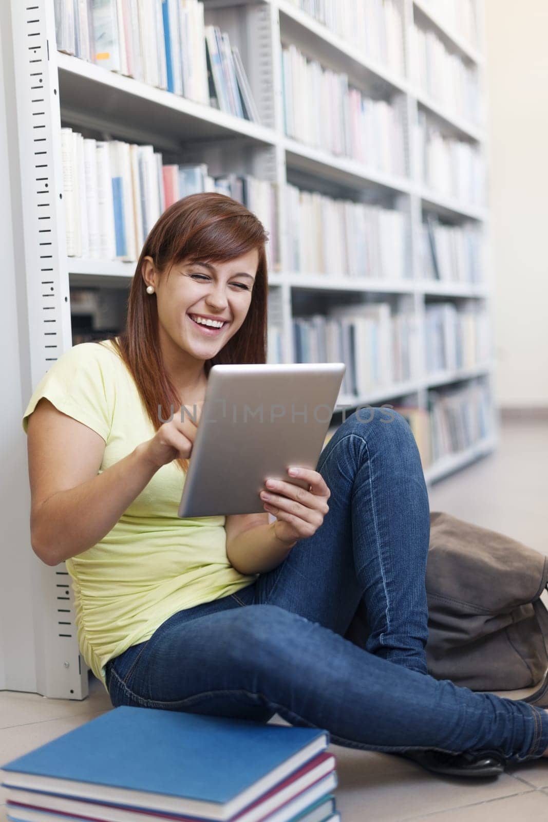 Happy student using digital tablet in library
