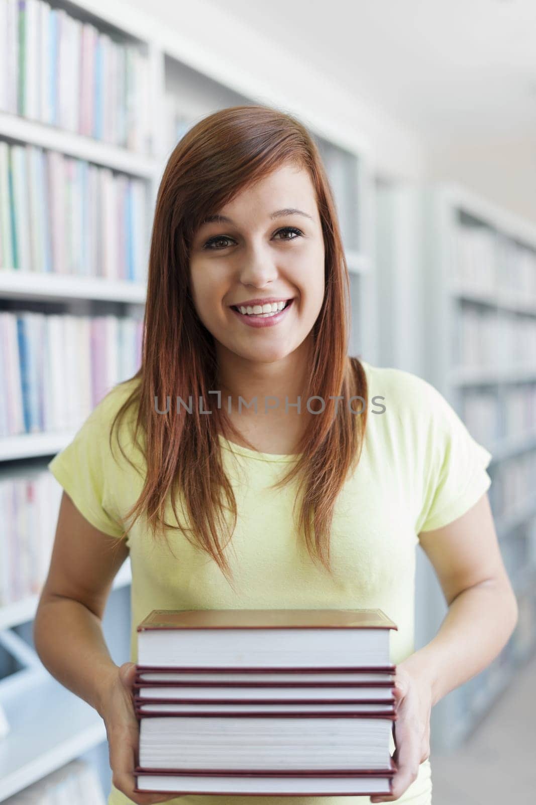 Beautiful student holding a books in library