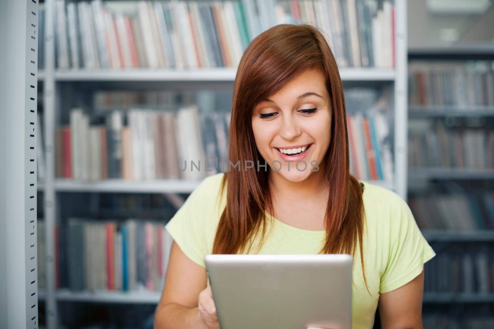 Happy student using digital tablet in library