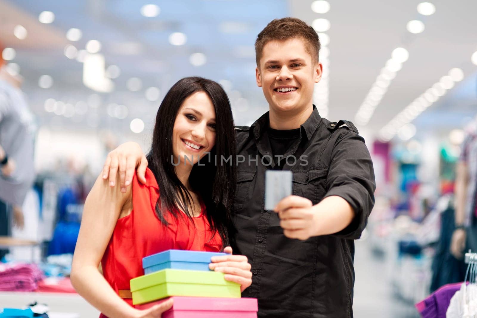 Happy young couple spending money at clothing store