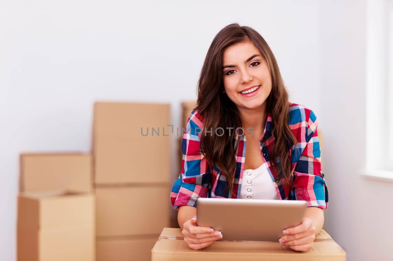 Young woman using digital tablet during moving in new apartment