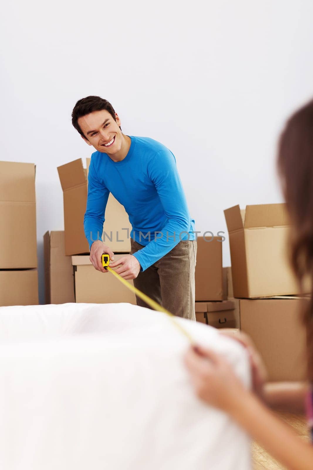 Smiling couple measuring the sofa in their new home