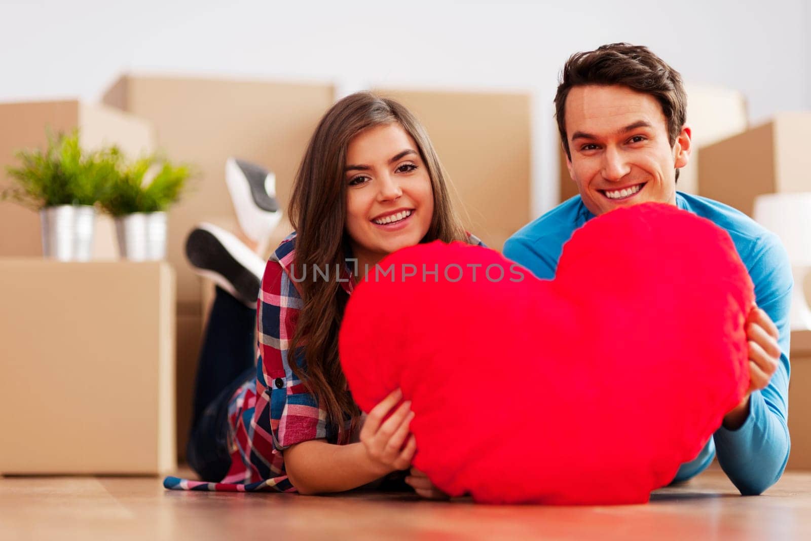 Young couple holding a heart shape in their new apartment