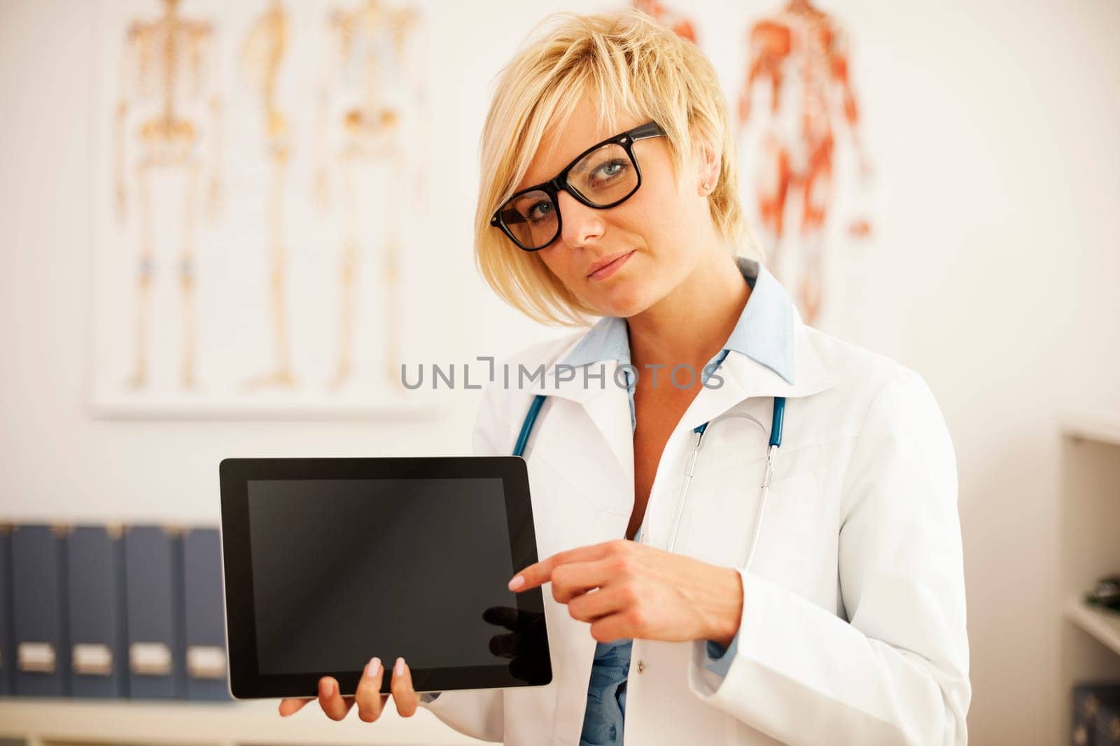 Serious female doctor pointing at digital tablet