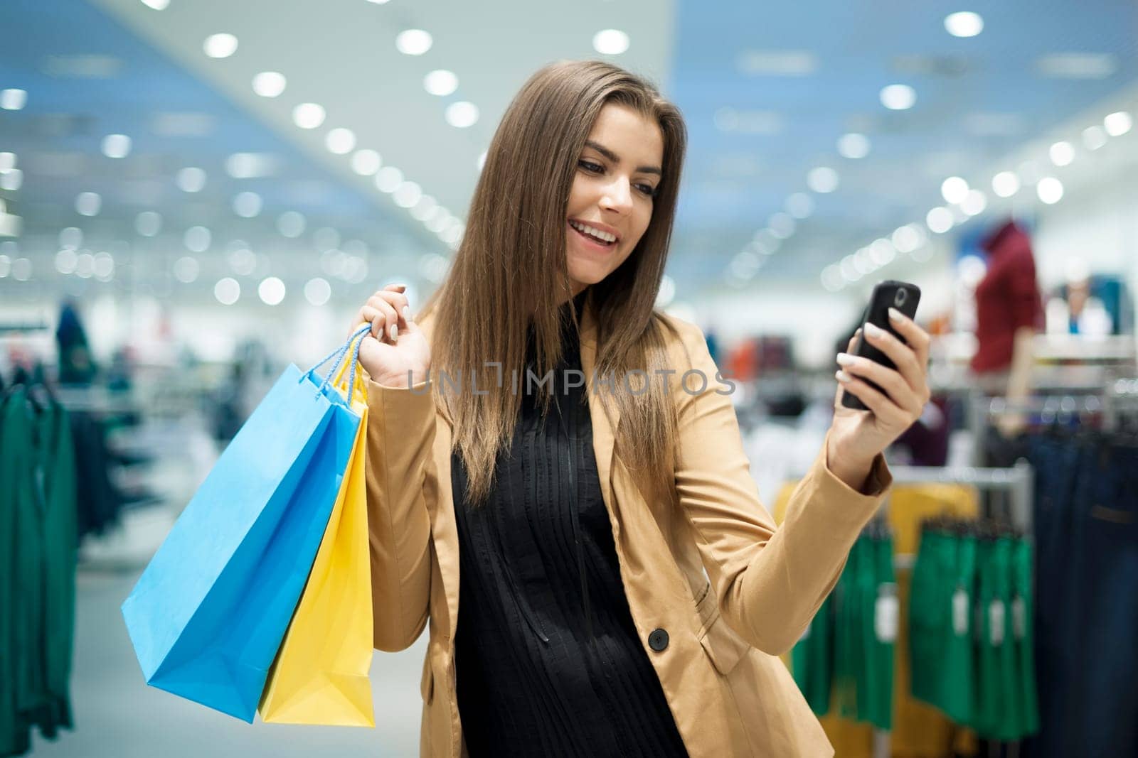 Cheerful female shopper texting on mobile phone