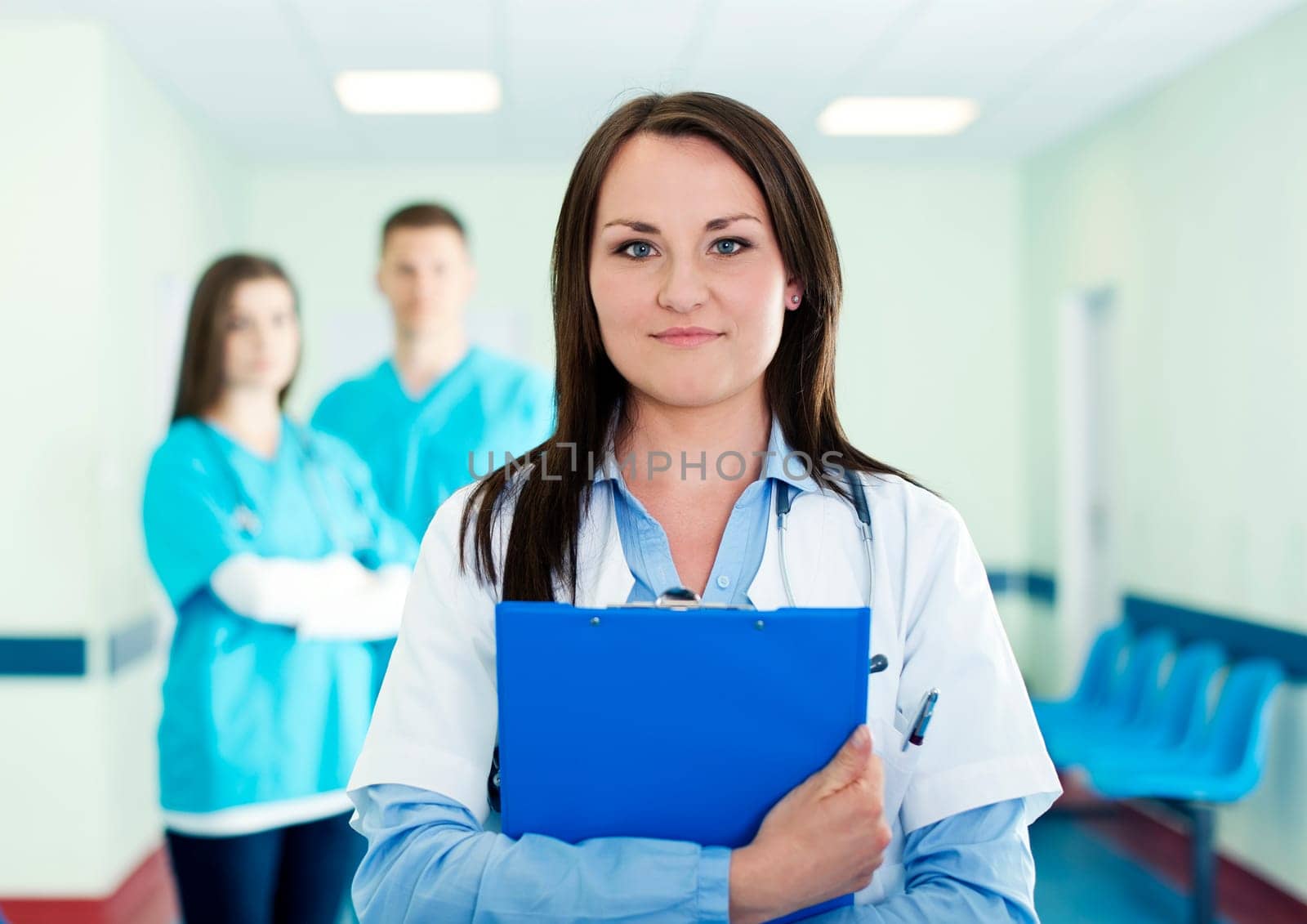 Portrait of young female doctor with interns in background