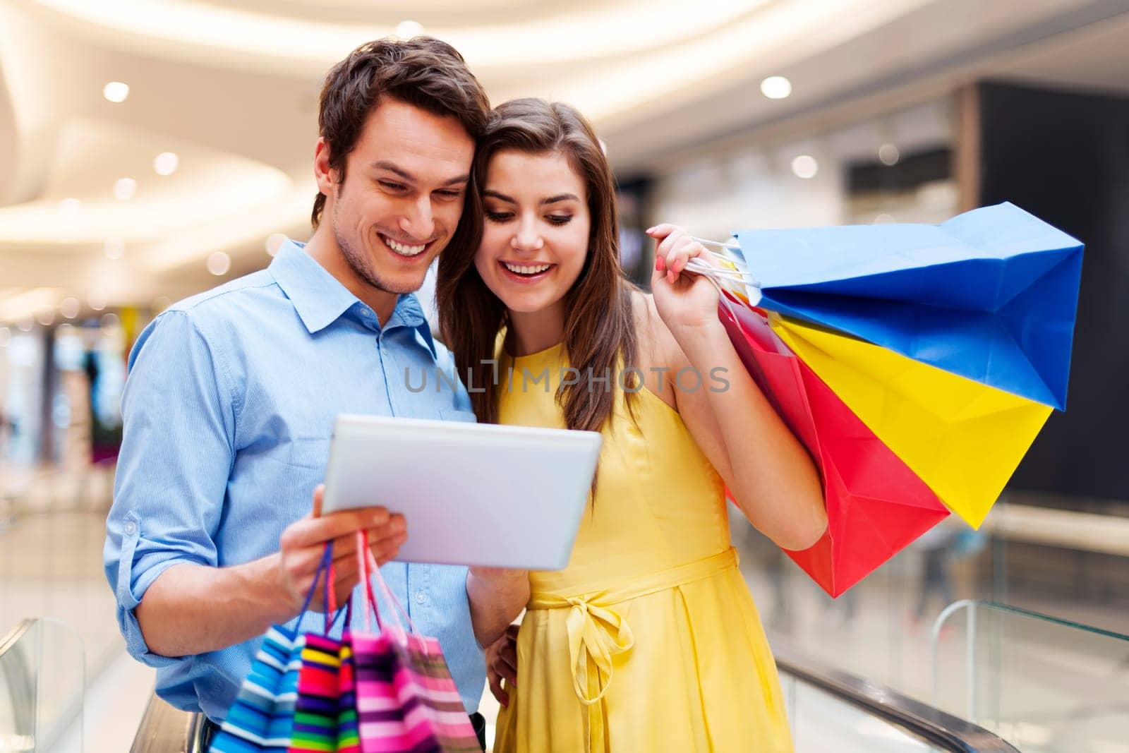 Happy couple using s digital tablet in the shopping mall