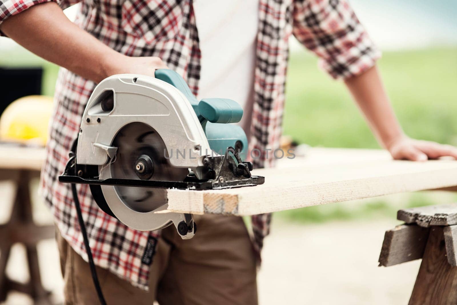 Close-up of carpenter cutting a wooden plank