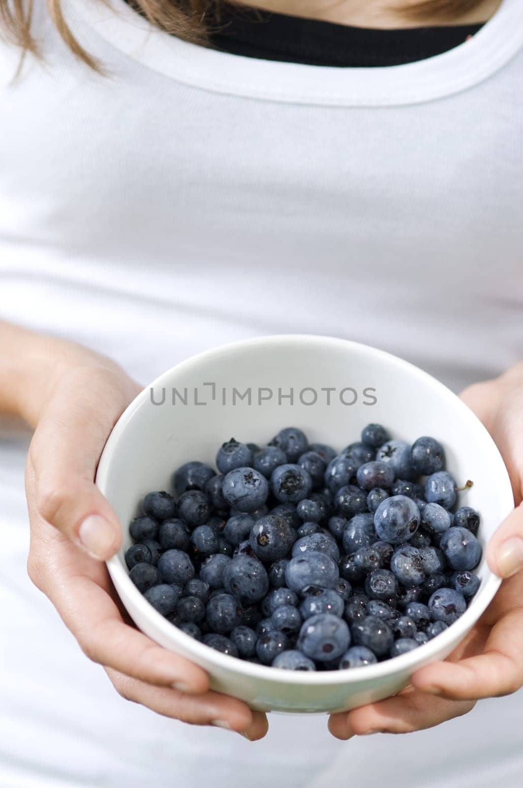 Young woman holding bowl filled blueberries