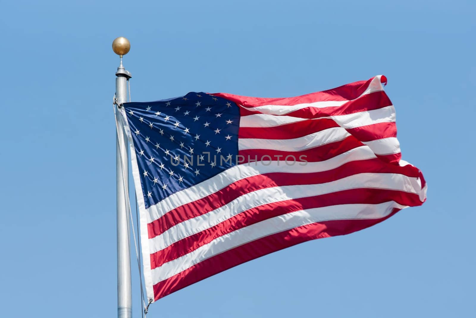 American flag fluttering on the blue sky