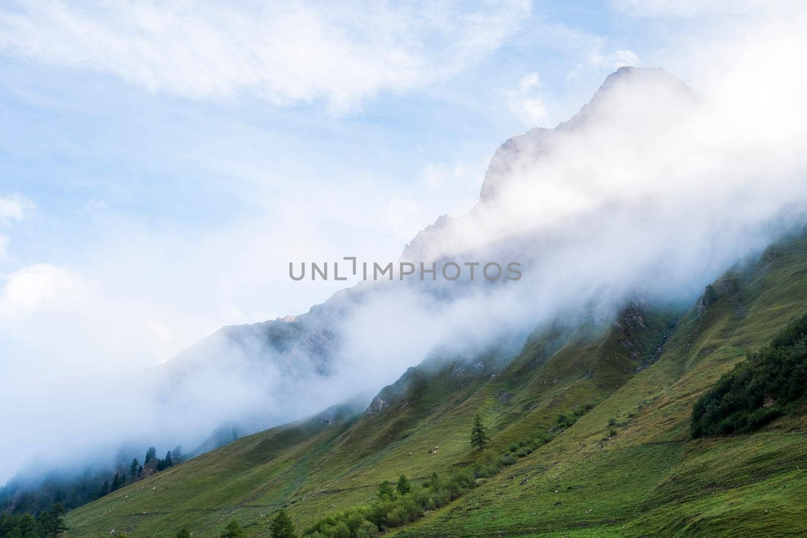 Clouds rolling down hillside in les Ars Dessus, Switzerland. The region is one of the stages in the popular Mont Blanc tour, which crosses France, Italy and Switzerland.