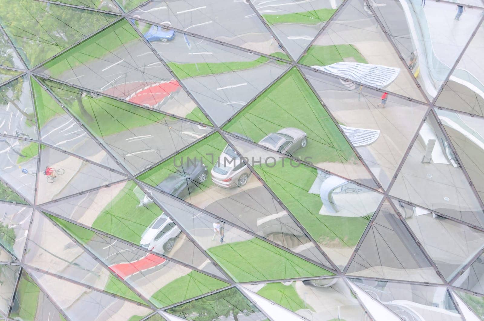 Urban lifestyle reflected in mirrored glass wall and divided into triangular parts of city
