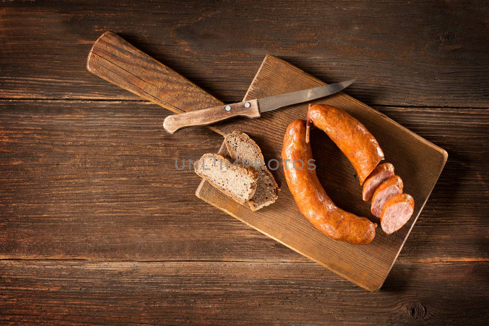the sliced tasty sausage with bread on the wooden table