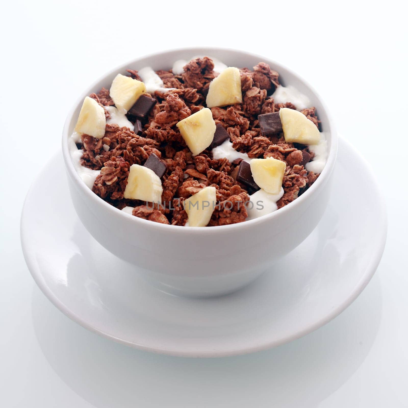 Bowl of tasty flavored chocolate breakfast cereal with diced fresh banana and chips of dark chocolate candy in a crunchy roasted muesli