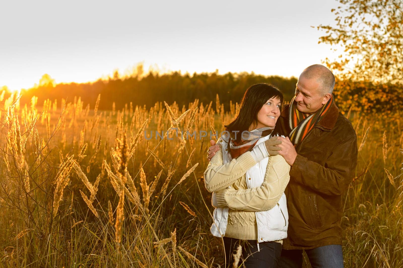Romantic couple hugging during autumn sunset countryside looking at each other