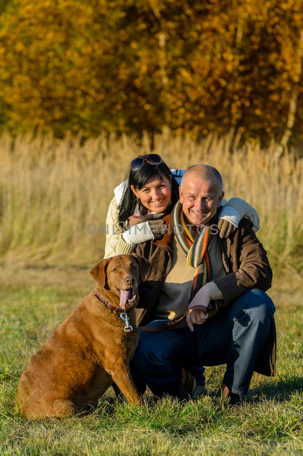 Cheerful couple with retriever dog in autumn park sunset