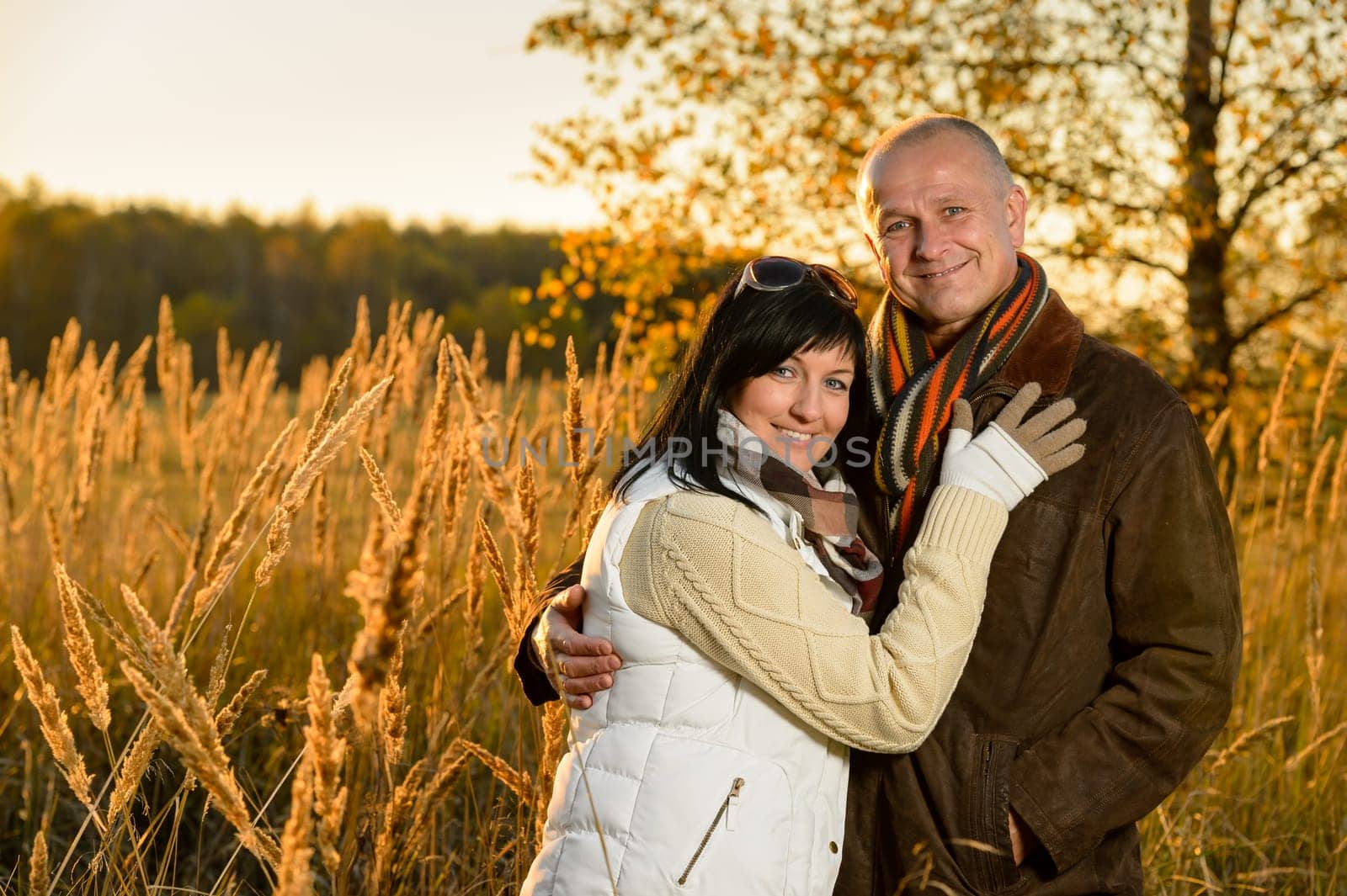 Couple in love embracing in autumn countryside backlit by sunset