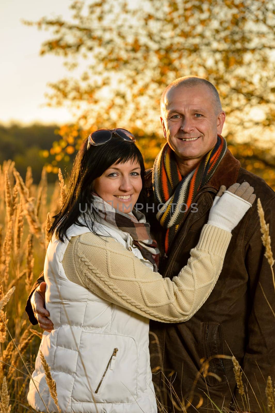 Romantic couple hugging in autumn countryside backlit by sunset