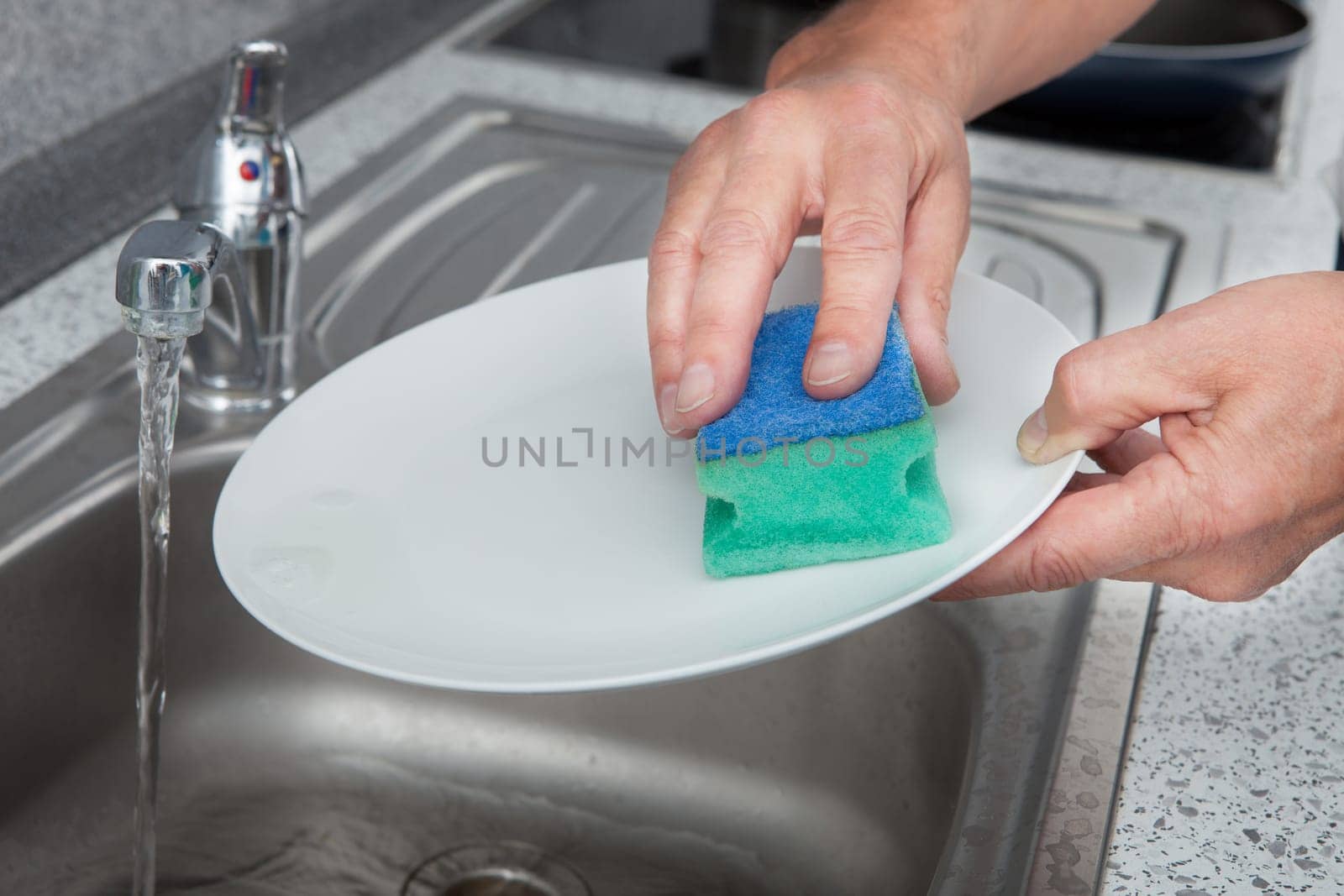 Close-up Of Hand Cleaning Plate With Scrubber