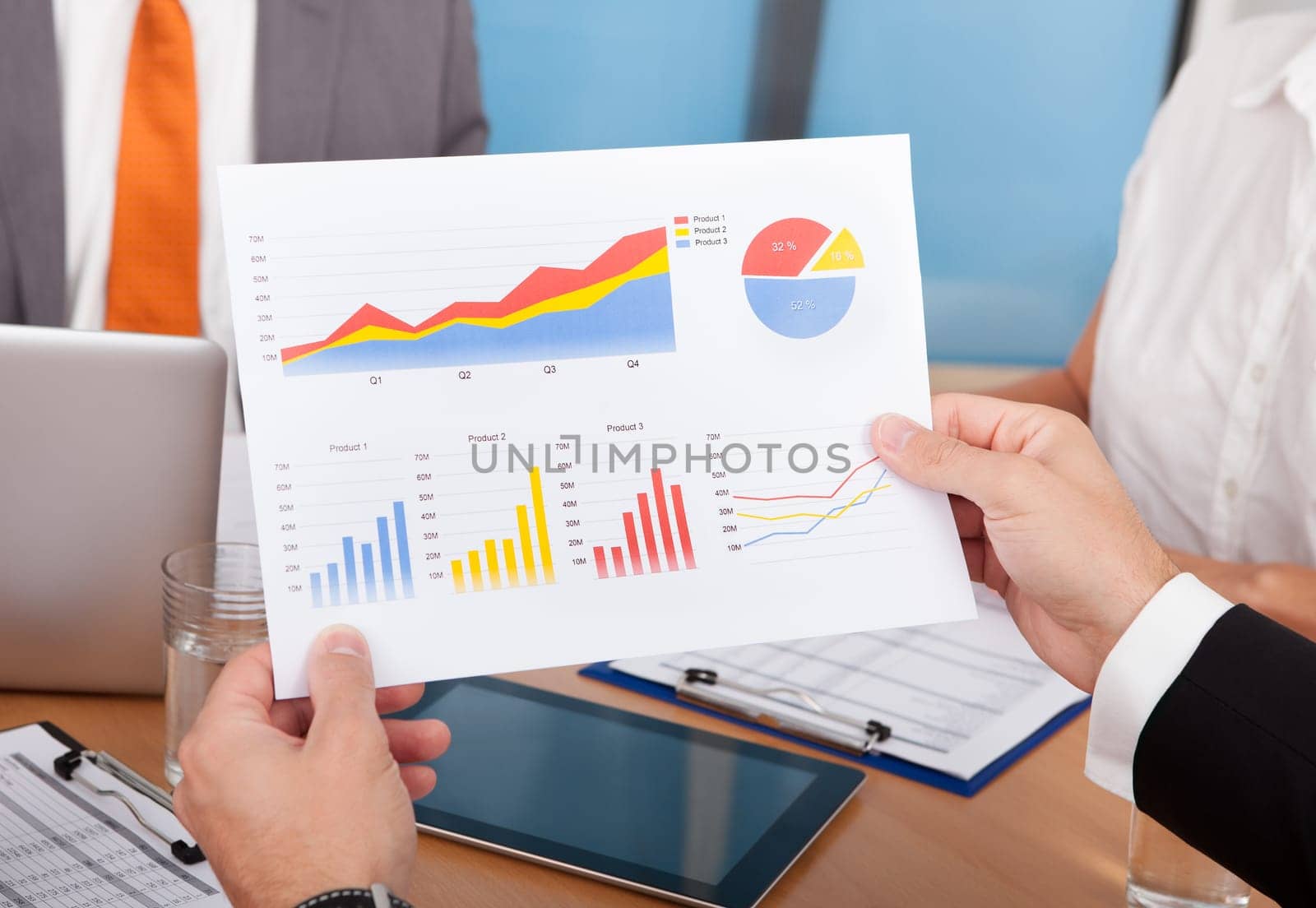 Close-up Of Businesspeople Analyzing Graph Together In Office