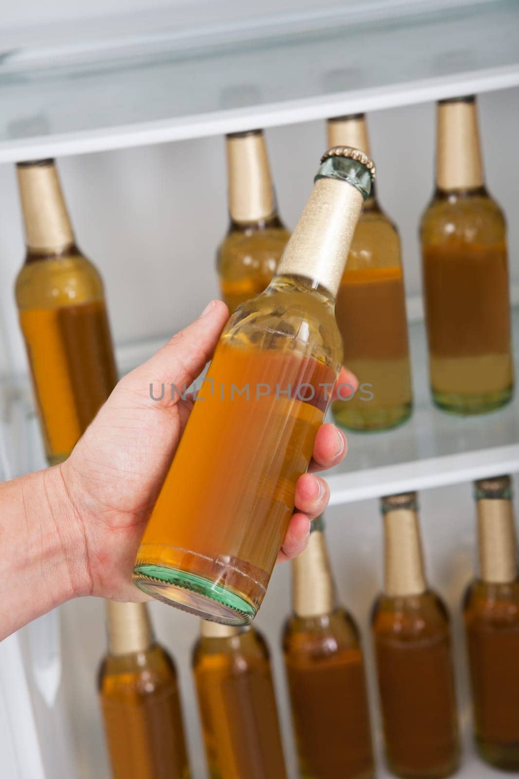 Man choosing bottle of beer from a refrigerator