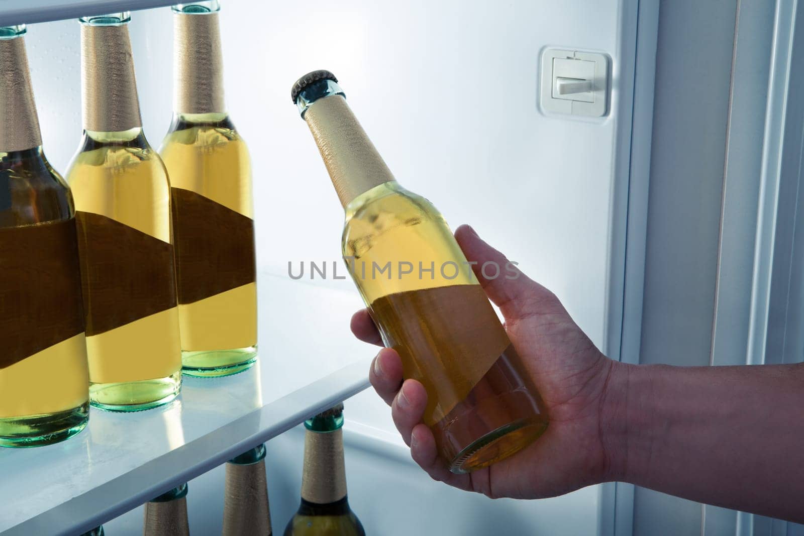 Man choosing bottle of beer from a refrigerator