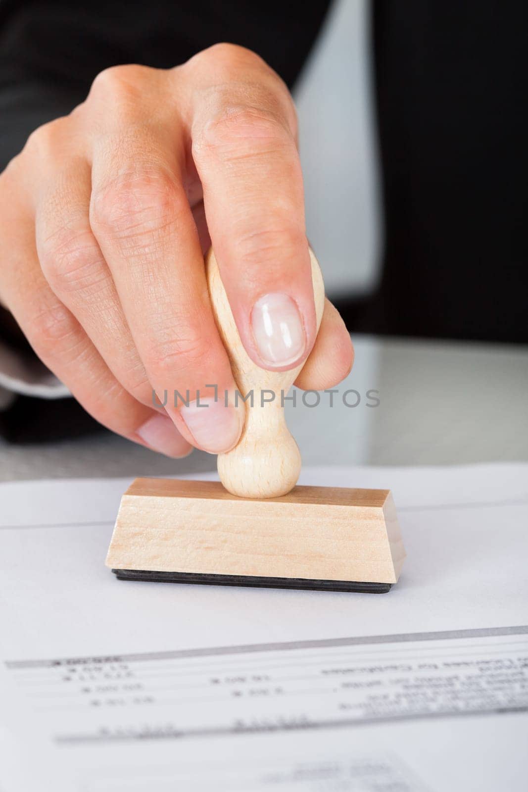 Close-up Of Business Man Hand Pressing Rubber Stamp On Document