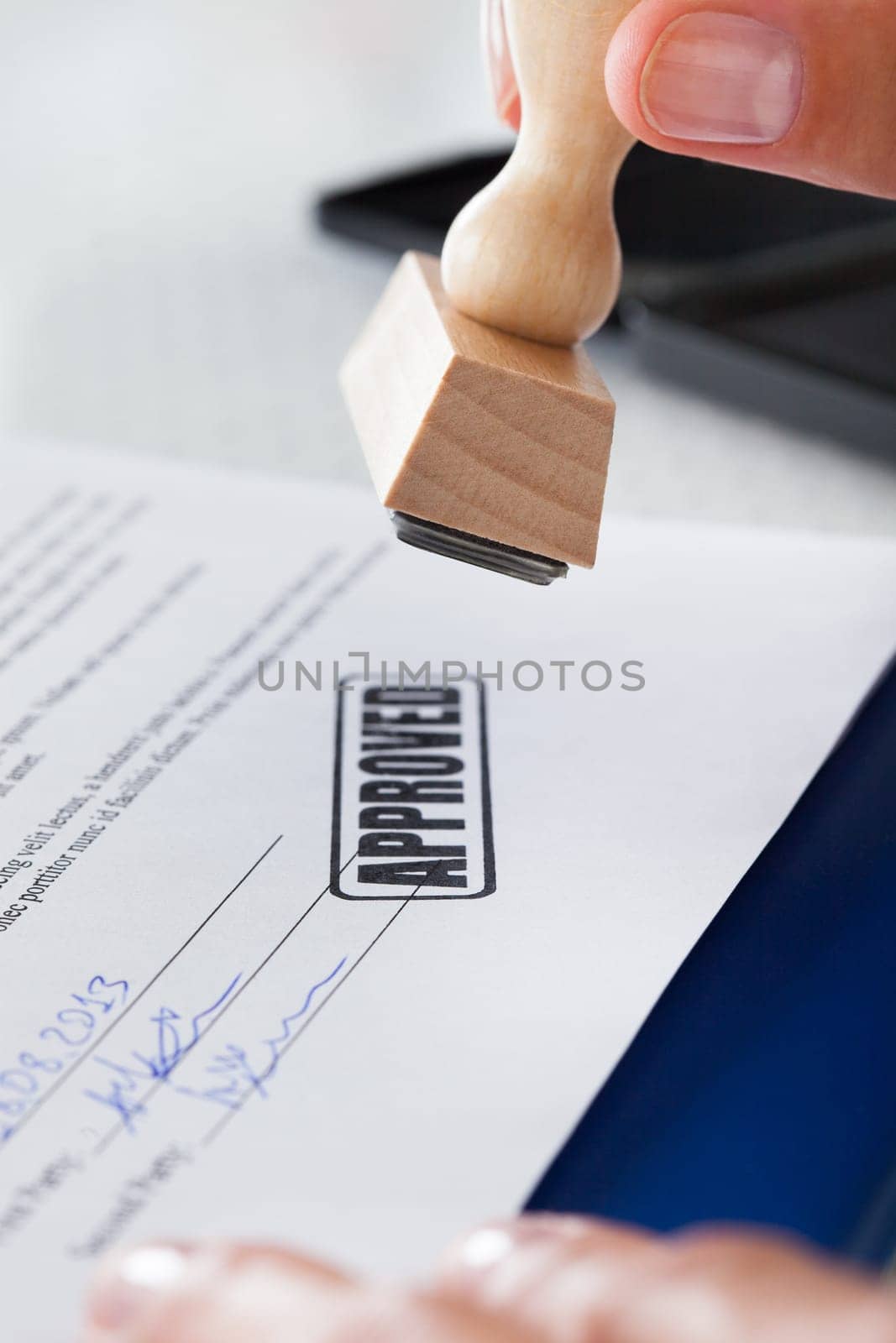 Close-up Of Business Man Hand Pressing Rubber Stamp On Document