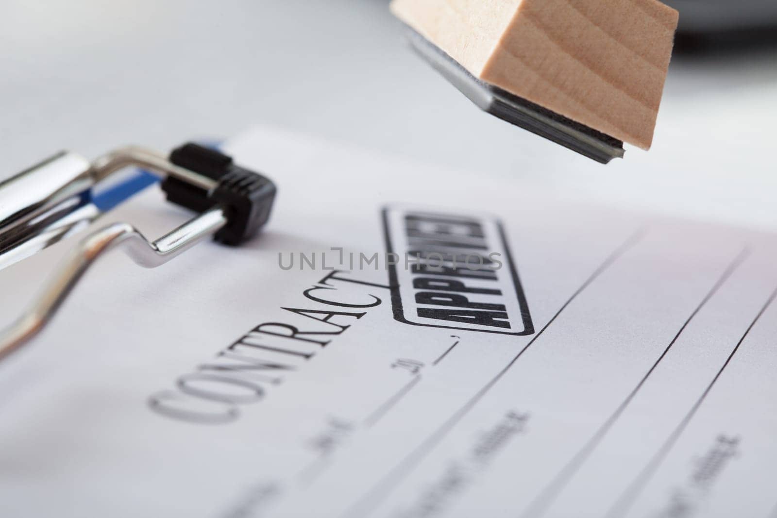 Close-up Of Business Man Hand Pressing Rubber Stamp On Document