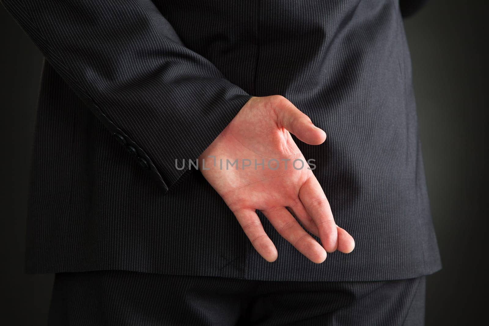 Rear View Of Businessman With Hands Behind Standing Over Black Background