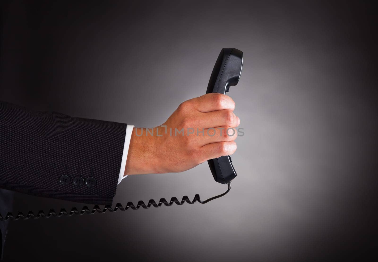 Close-up Of Hand Holding Telephone Receiver Over Black Background