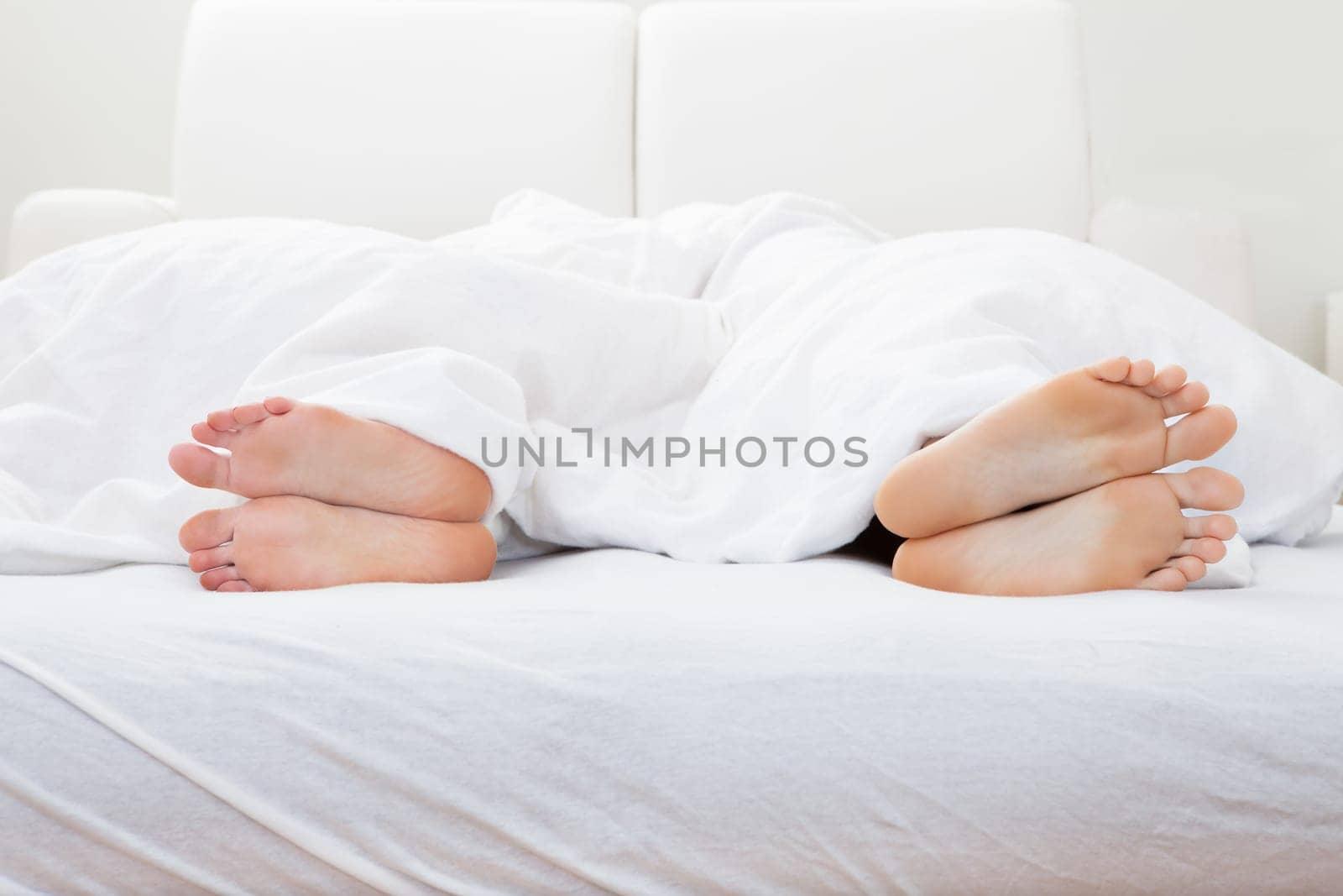 Close-up of couple's feet sleeping on bed in bedroom