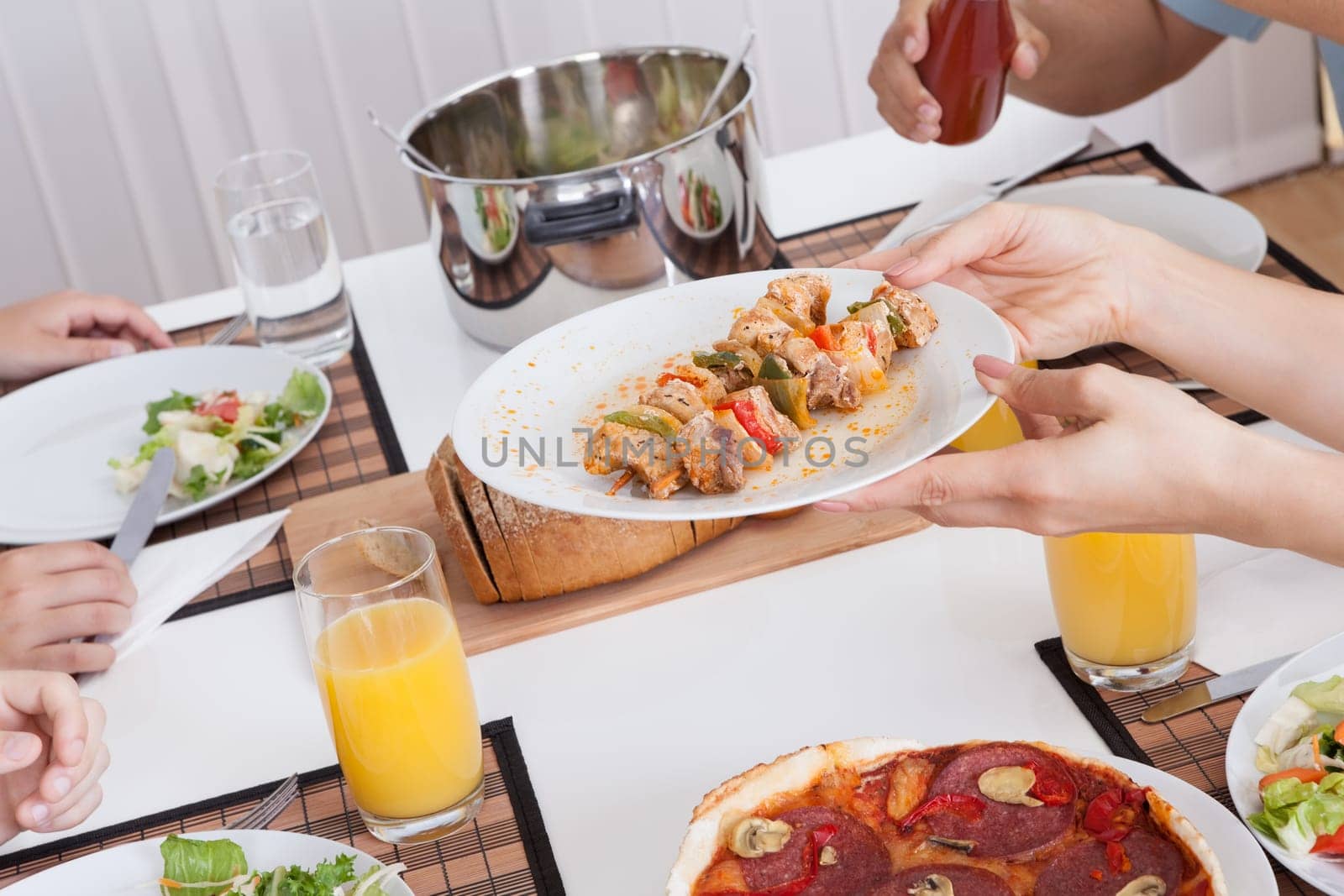 Young happy family with teenage children sitting down to eat a cold lunch of meat and salads