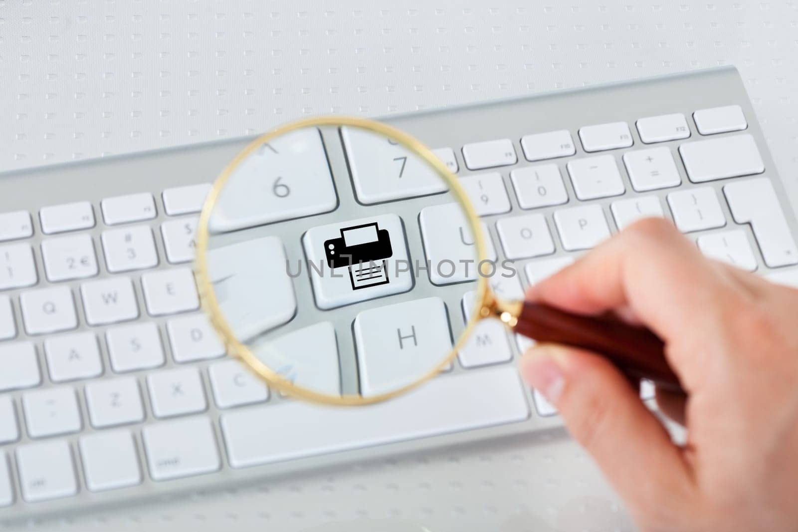 Close-up of hand looking at printer key through magnifying glass