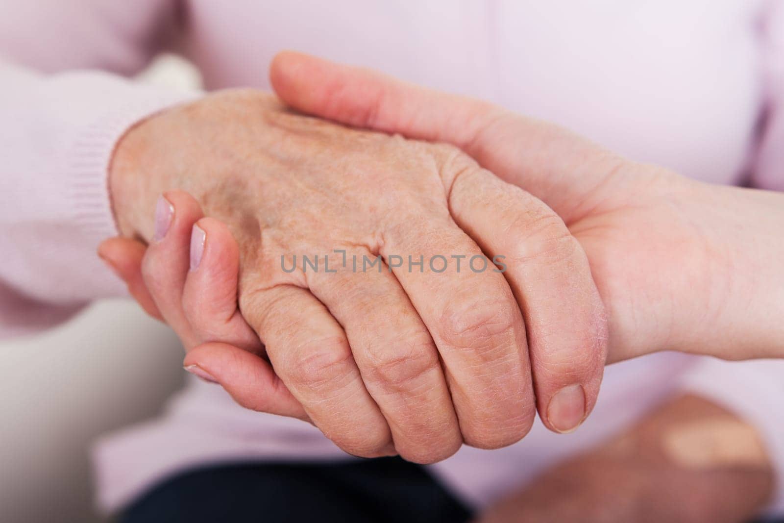 Young Woman Holding Senior Woman's Hand  Indoor