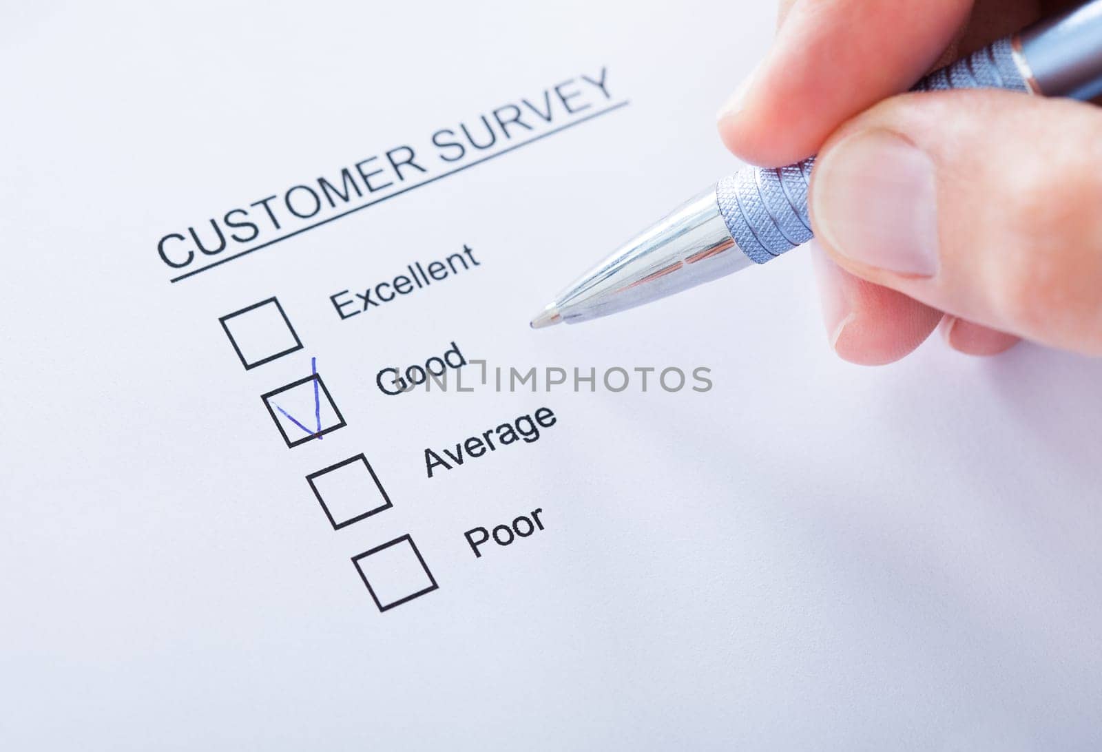 Close-up Of Human Hand Filling Customer Survey Form