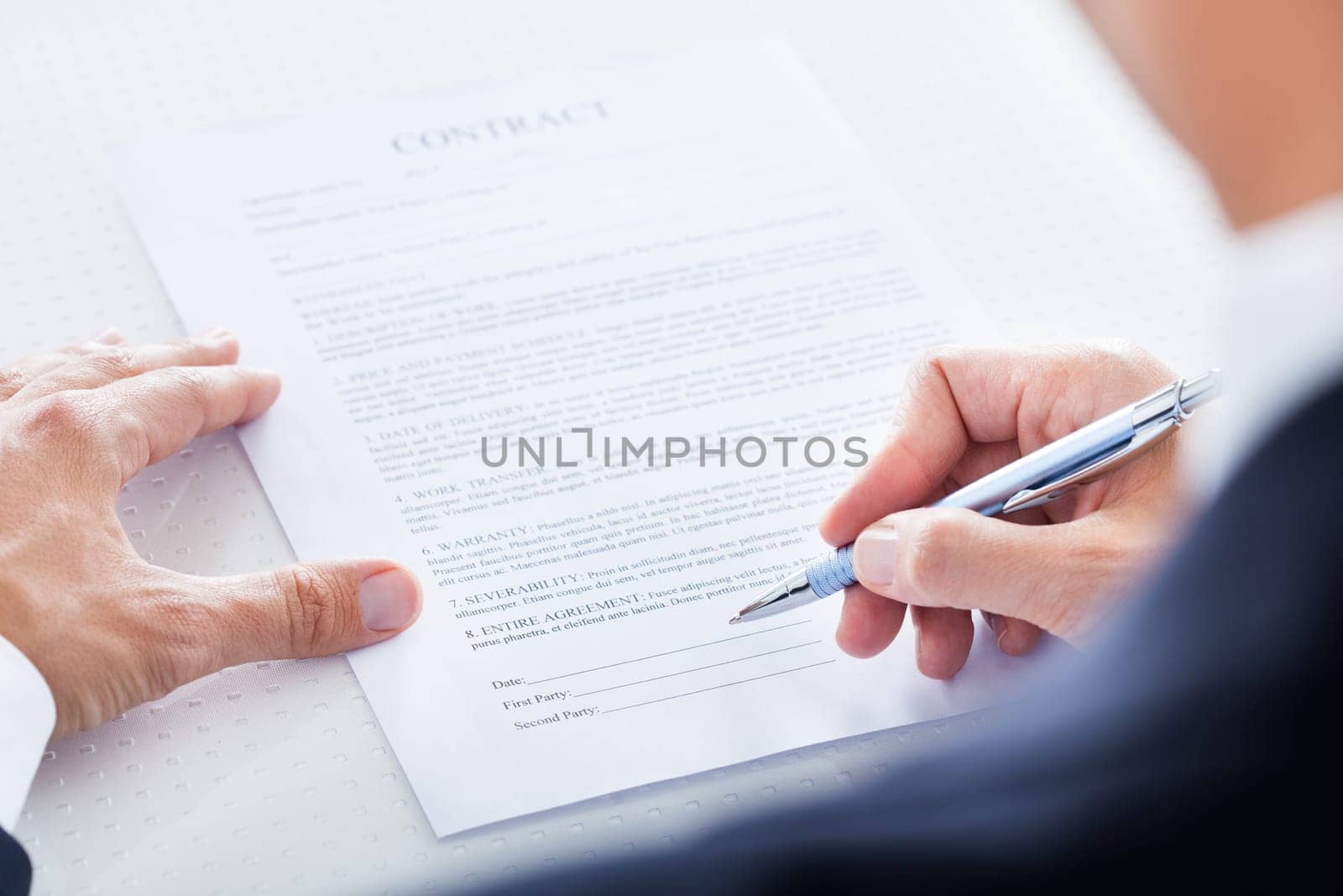 Close-up Of Businessman Holding Pen To Sign On Contract Paper